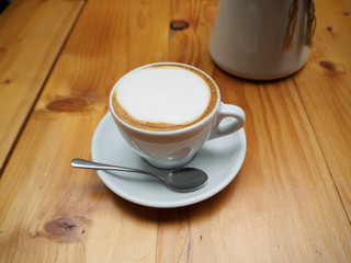 Cappuccino in a white cup on wooden background