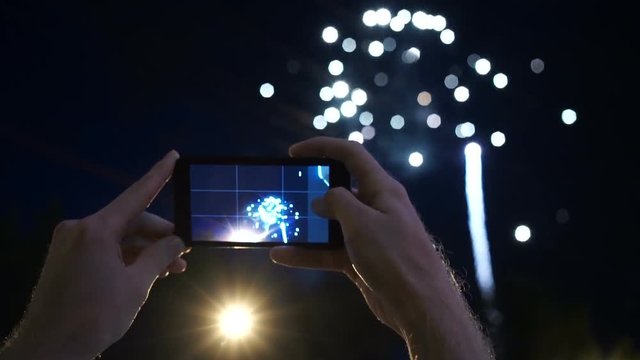 hands of man taking the photo to fireworks with the new smartphone