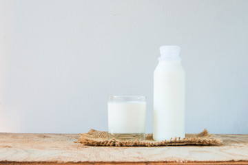 A glass of rustic milk and bottle of rustic milk on a wood table