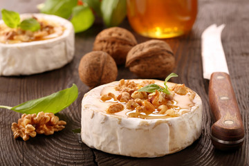 Grilled cheese with honey and nuts on old wooden background