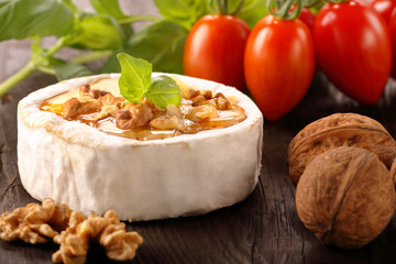 Grilled cheese with honey and nuts on old wooden background