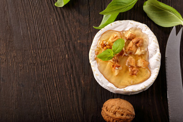 Grilled cheese with honey and nuts on old wooden background