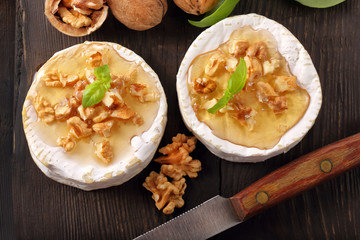 Grilled cheese with honey and nuts on old wooden background