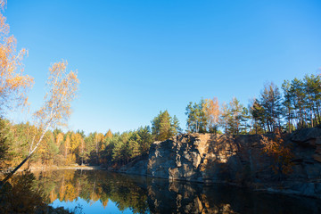 Fragment of the lake shore with stone in autumn forest