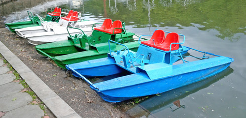 Pedal boats of various colors are on the lake