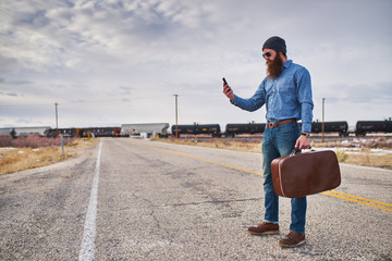 lost bearded hitch hiker with smart phone looking for directions on desolate nevada road