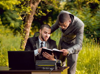 Two young businessman at work in the park.