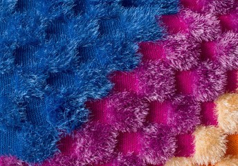 A fragment of a bright colored knit plaid, home-made, crocheted blanket background of shaggy thread, Colorful shawls closeup