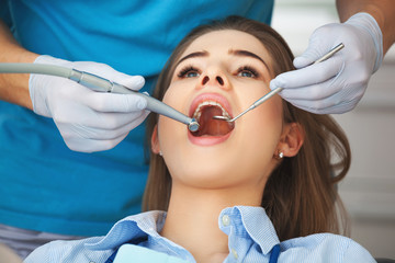 Naklejka premium Young woman getting her teeth checked by a dentist.