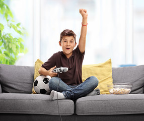 Joyful kid playing football video game