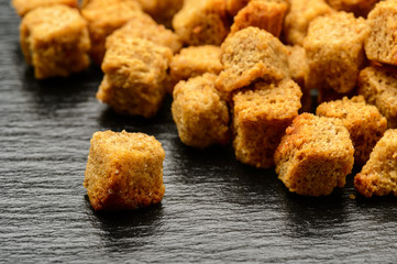 Rye bread croutons on black background.
