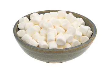 Small marshmallows in an old stoneware bowl isolated on a white background.