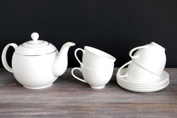 Tea pot, tea cups. Wooden table, black background. Chinese porcelain.