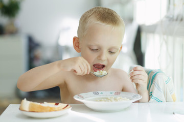 boy; kid; child eating; boy eating soup; plate; kitchen; 