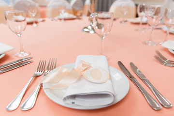 Plate with napkin with pink ribbon on wedding table in restaurant