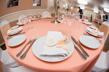 Plate with napkin with pink ribbon on wedding table in restaurant