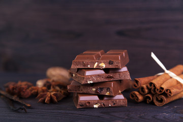 Broken chocolate bar with cinnamon, anise and nutmeg on a dark wooden background
