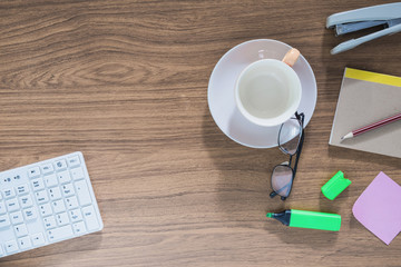 empty coffee cup with glasses on wooden office table with copy s