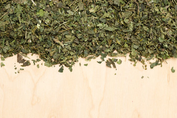 Dried nettle leaves on wooden board with copy space