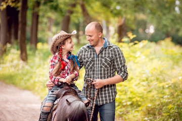 Beautiful little girl on a pony with his father.