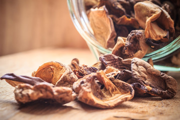 Dry mushrooms in jar on wooden table.