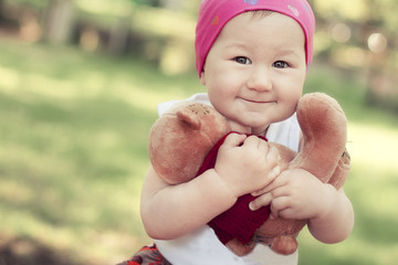 happy little girl in cap playing with Teddy bear