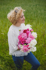  beautiful women with a peonies in the green field, short blonde hair, white t-shirt