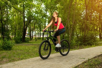 Happy girl cyclist riding on a mountain bike outside