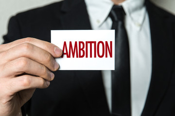 Business man holding a card with the text: Ambition