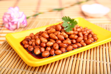 Fried peanuts with sauce on yellow plate on the table in restaurant