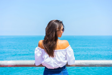 Young beautiful woman looking on sea and sky. Back view.
