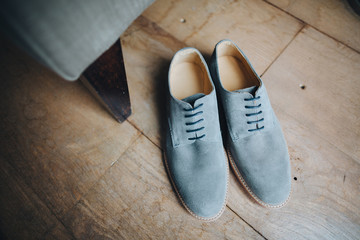 Wedding. Mountains . Footwear. Artwork. Grain. Blue suede shoes standing on the wooden floor next to the chair