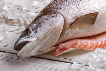 Raw fish and ice cubes. Head of fresh fish. Salmon was bought in shop. Good catch of fisherman.