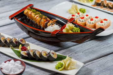 Sushi boat and plates. Different sushi rolls. Cream cheese and fresh tuna. Feast for sushi lovers.