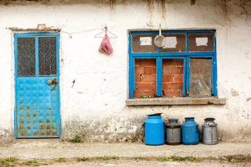 old milk jugs in a row in front of an abandoned house
