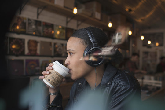 Young woman listening to music while drinking coffee