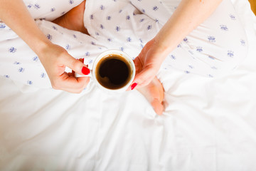 woman on bed with cup of coffee