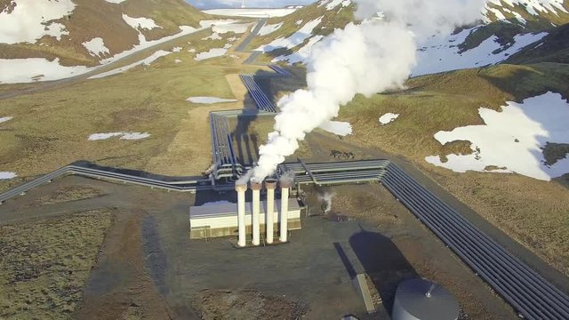 Aerial view of a geothermal power plant in Iceland. Steam rising upp against the sunlit sky from the plant