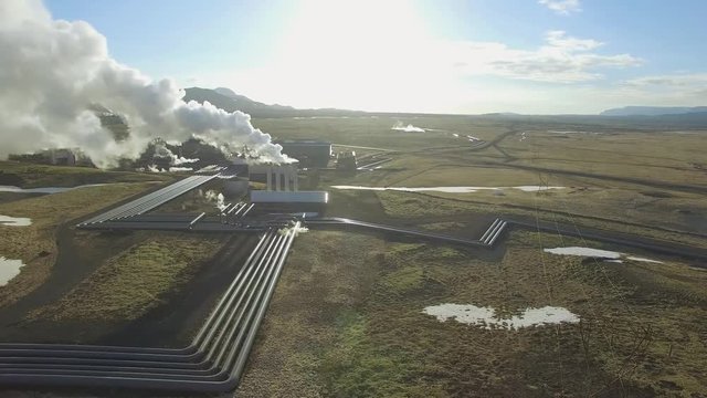 Aerial view of a geothermal power plant in Iceland. Steam rising upp against the sunlit sky from the plant
