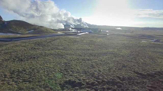 Aerial view of a geothermal power plant in Iceland. Steam rising upp against the sunlit sky from the plant