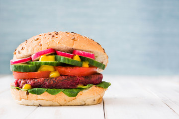 Veggie beet burger on white wooden and blue background

