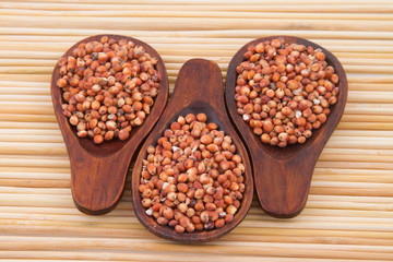 gluten free grains, millet, sorghum and linseed spoon on wooden natural background
