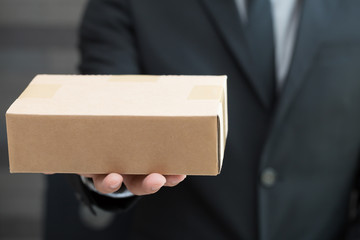 Businessman in suit giving brown box to someone