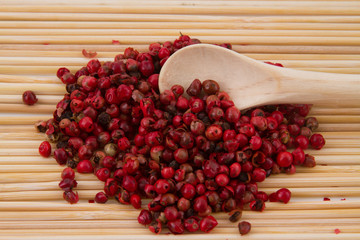 pink pepper with spoon and wooden background