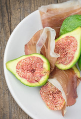 Figs and ham on white plate