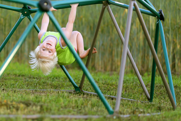 Little Child Playing at PLayground Climbing on Monkey Bars
