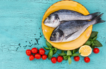 Raw dorado fish on plate, blue table. Top view, copy space.