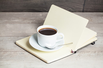 Cup of coffee on a wooden table with book