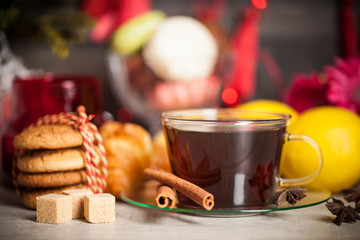 Christmas time, cup of tea with cinnamon and anise spices, festive decoration and candles on wood background.