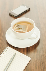 Hot tea in a white cup with notepad